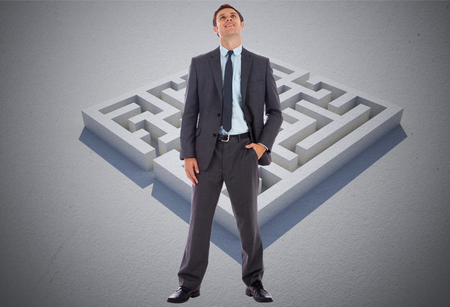 Happy businessman with hand in pocket against maze puzzle の写真素材