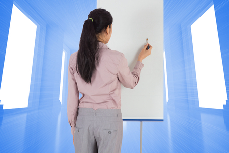 Businesswoman painting on an easel against bright blue room with windowsの写真素材
