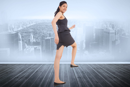 Businesswoman stepping up against city scene in a roomの写真素材