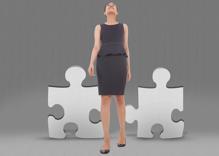 Asian businesswoman walking against grey jigsaw piecesの写真素材