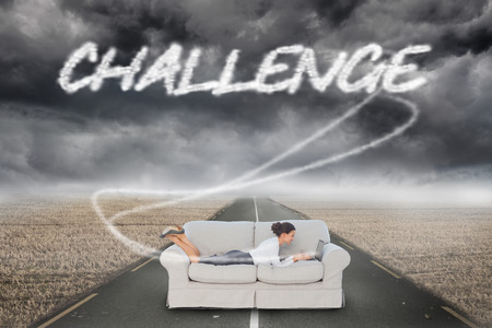 The word challenge and business woman lying on couch against misty brown landscape with streetの写真素材