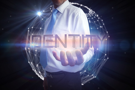 Businessman presenting the word identity against glowing sphere on black backgroundの写真素材