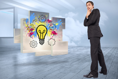 Thinking businessman touching chin against room with holographic cloudの写真素材