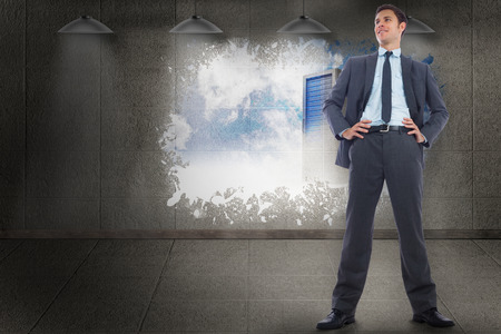 Happy businessman with hands on hips against splash on wall revealing server towerの写真素材