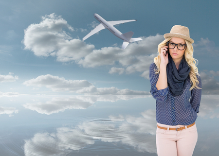 Serious trendy blonde on the phone against peaceful water and skyの写真素材