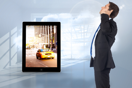 Thinking businessman scratching head against room with holographic cloudの写真素材