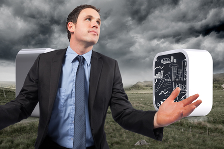 Businessman posing with arms out against stormy countryside backgroundの写真素材