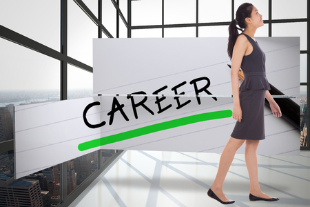 Asian businesswoman walking against room with large window showing cityの写真素材