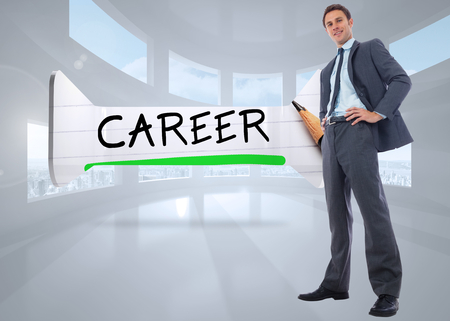Happy businessman with hands on hips against bright white room with windowsの写真素材