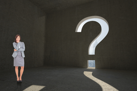 Smiling thoughtful businesswoman against question mark door in dark roomの写真素材