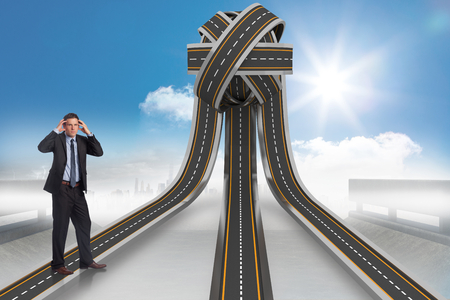 Stressed businessman with hands on head against tangled roads in a ballの写真素材