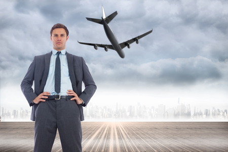 Stern businessman with hands on hips against city on the horizonの写真素材