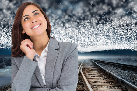 Smiling thoughtful businesswoman against train tracks under blanket of bright stars