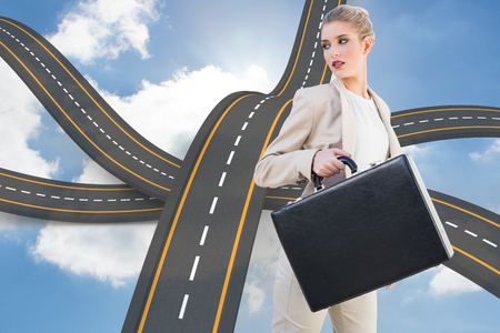 Serious elegant businesswoman holding briefcase against bumpy road backdropの写真素材