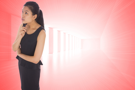 Thoughtful businesswoman against bright red room with windowsの写真素材