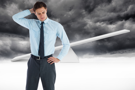 Thinking businessman with hand on head against white scales in front of storm cloudsの写真素材