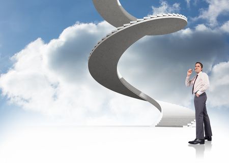 Thinking businessman holding glasses against spiral staircase in the skyの写真素材