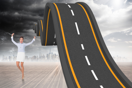 Excited brunette businesswoman jumping and cheering against bumpy road backdropの写真素材