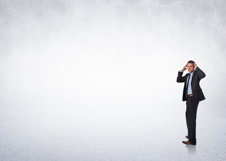 Stressed businessman with hands on head against white wallの写真素材