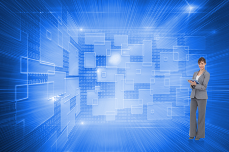 Smiling businesswoman with tablet computer against shiny technological backgroundの写真素材