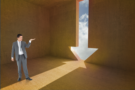 Businessman looking at what he is presenting against arrow door in dark roomの写真素材