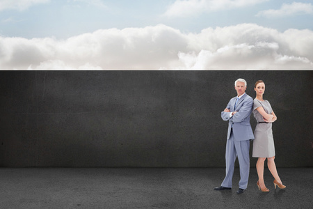 Serious businessman standing back to back with a woman  against balcony and bright skyの写真素材