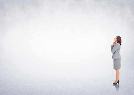 Smiling thoughtful businesswoman against white wallの写真素材