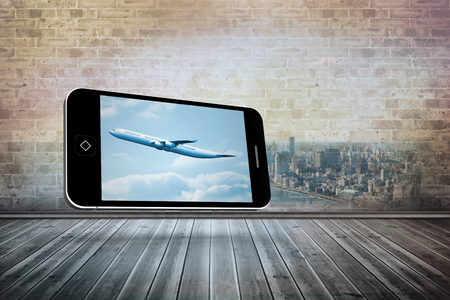 Airplane on smartphone screen against city scene in a roomの写真素材
