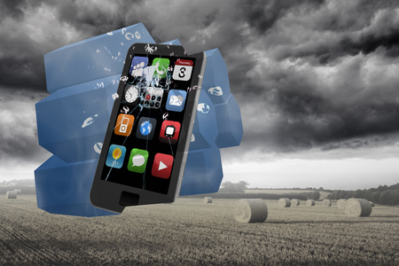 Smartphone on abstract screen against misty landscape with bales of strawの写真素材