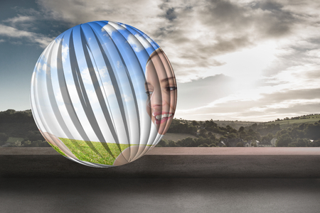 Smiling woman in field on abstract screen against view of landscape from balconyの写真素材
