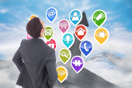 Businessman standing with hands on hips against road turning into arrowの写真素材