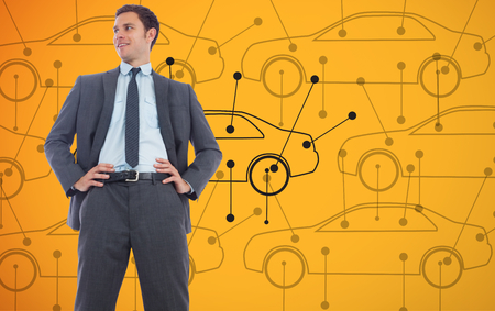 Cheerful businessman with hands on hips against car diagrams on yellow backgroundの写真素材
