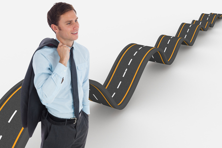 Smiling businessman holding his jacket against bumpy road backgroundの写真素材