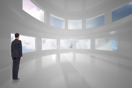 Businessman turning his back to camera against sun shining through windowsの写真素材