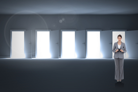 Young businesswoman with binoculars against doors opening revealing lightの写真素材