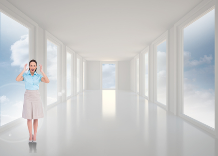 Surprised stylish businesswoman posing against bright white hall with windowsの写真素材