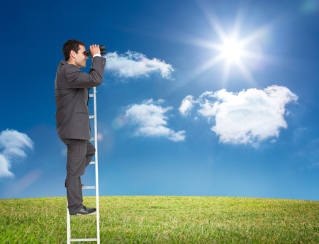 Composite image of businessman standing on ladder holding binocularsの写真素材