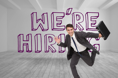 Businessman running in front of were hiring graphic in grey roomの写真素材