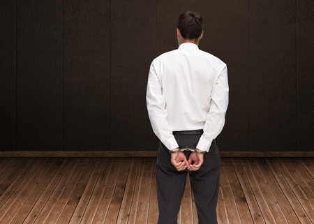 Composite image of rear view of young businessman wearing handcuffs
