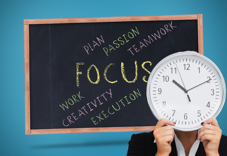 Composite image of businesswoman in suit holding a clockの写真素材