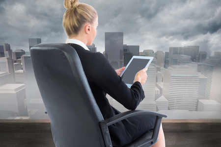 Composite image of blonde businesswoman sitting on swivel chair with tabletの写真素材
