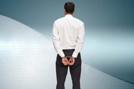 Composite image of rear view of young businessman wearing handcuffsの写真素材