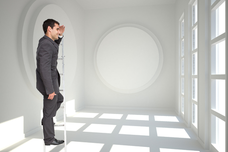 Composite image of happy businessman standing on ladder peeringの写真素材