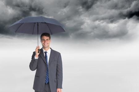 Composite image of happy businessman holding grey umbrellaの写真素材