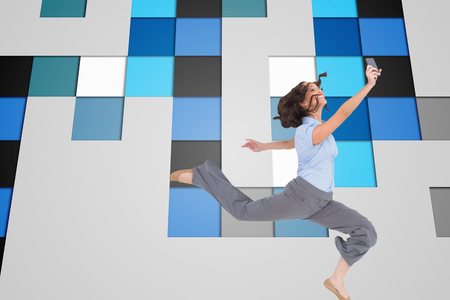 Composite image of happy classy businesswoman jumping while holding smartphoneの写真素材