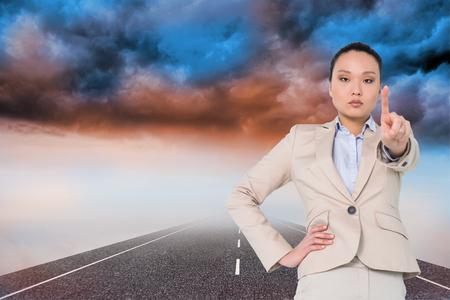 Composite image of unsmiling asian businesswoman pointingの写真素材
