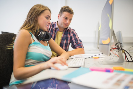Cheerful classmates doing an assignment together in the computer room in collegeの写真素材