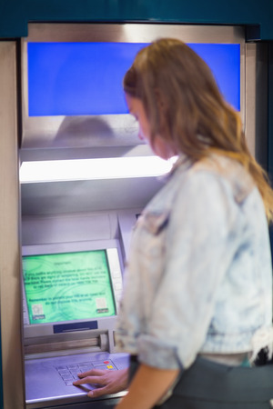 Student entering pin at the atm in collegeの写真素材