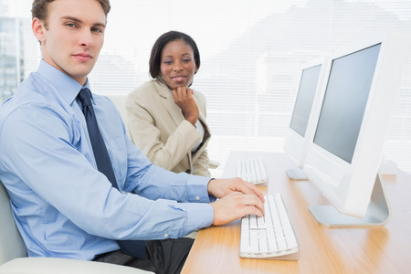 Side view portrait of business colleagues using computers at office desk