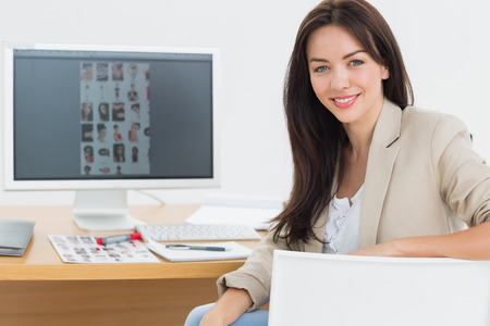 Portrait of a female artist sitting at desk with computer in the officeの写真素材